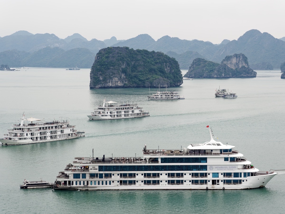 Kapal pelayaran di antara pulau batu kapur di Teluk Ha Long